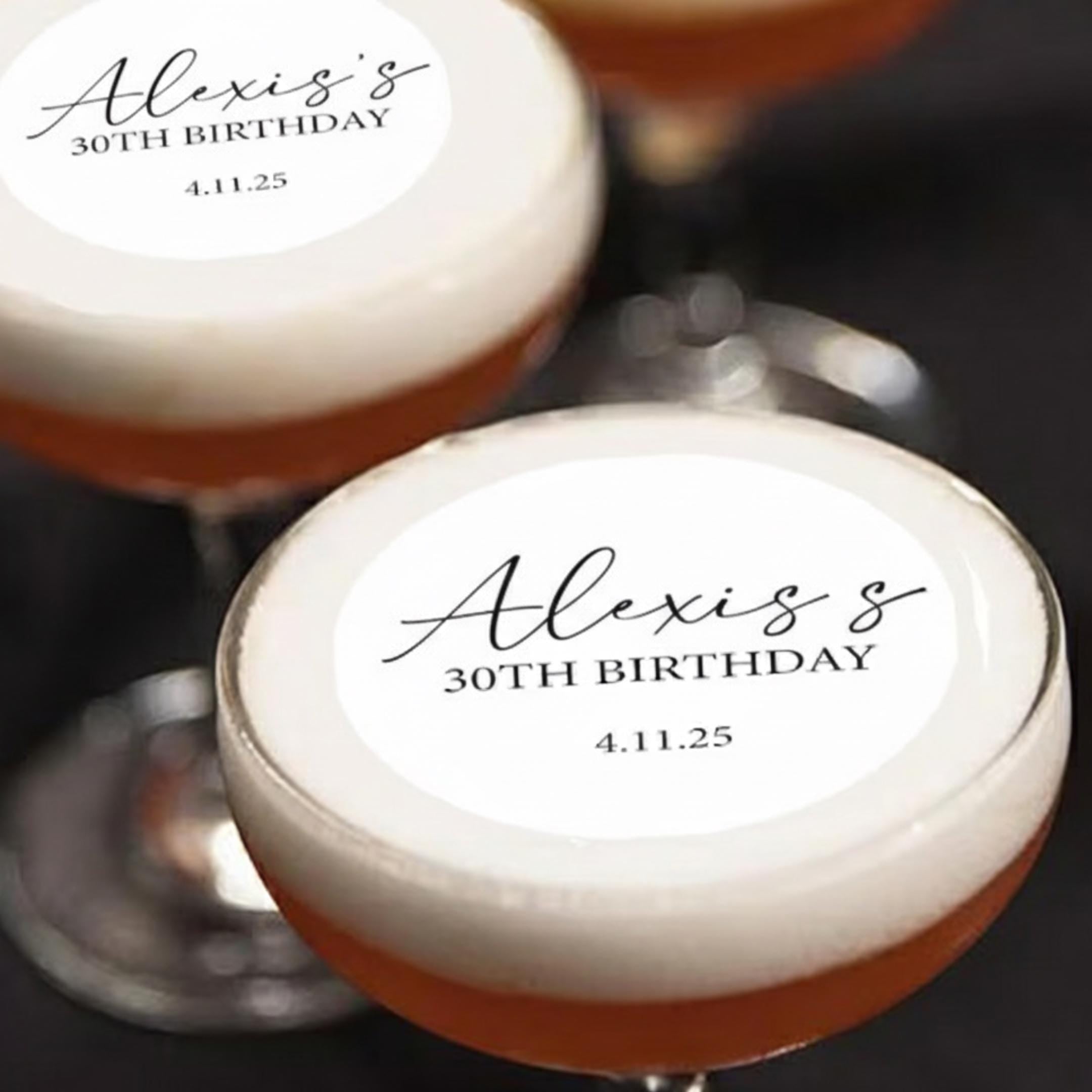 Custom Cocktail Toppers Cocktail glasses filled with an orange-hued liquid and topped with a white foam. Each glass has a circular label with the name "Alexis's", "30TH BIRTHDAY", and the date "4.11.25" in black script.