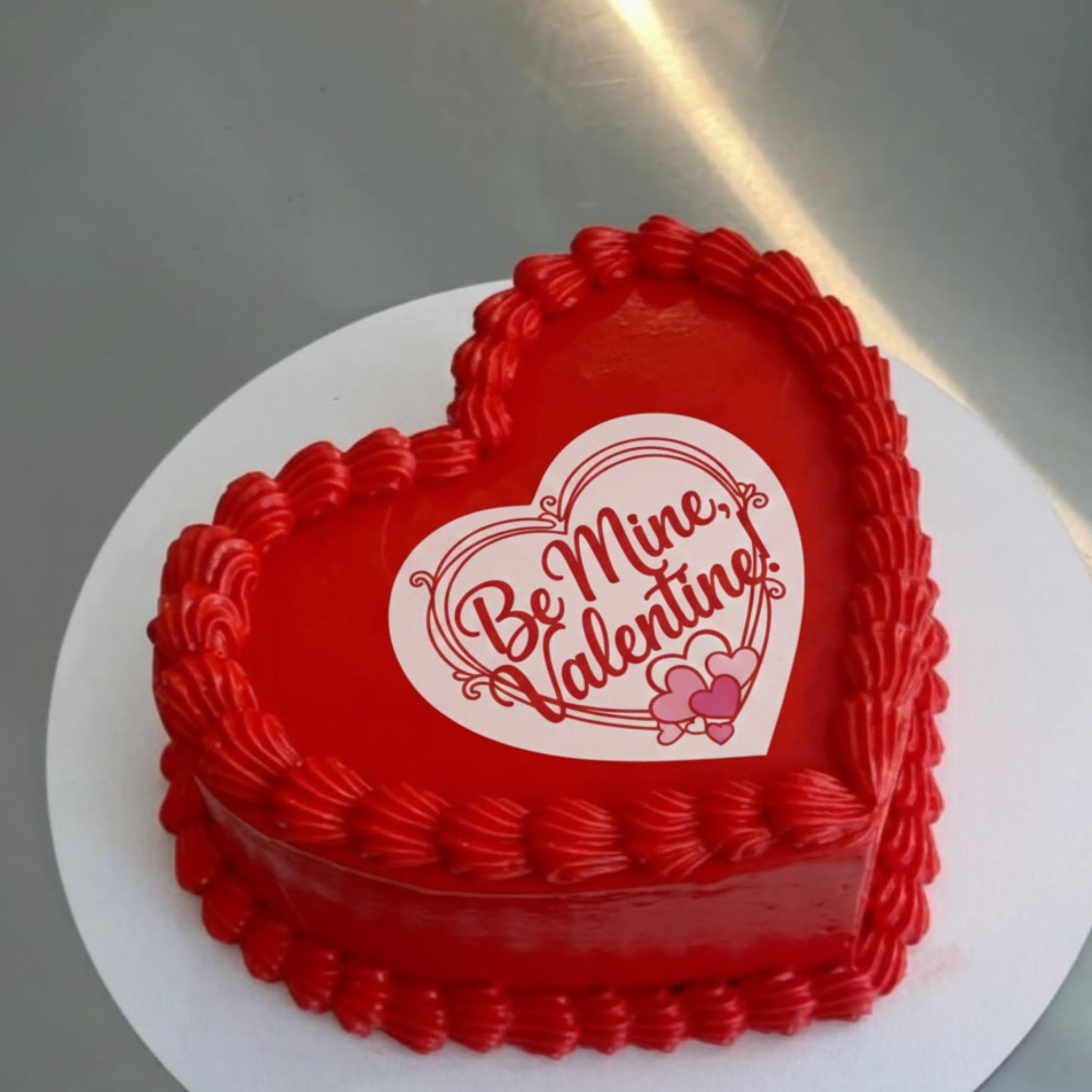 Round icing sheet cake topper with red heart frame and text Be Mine Valentine in script