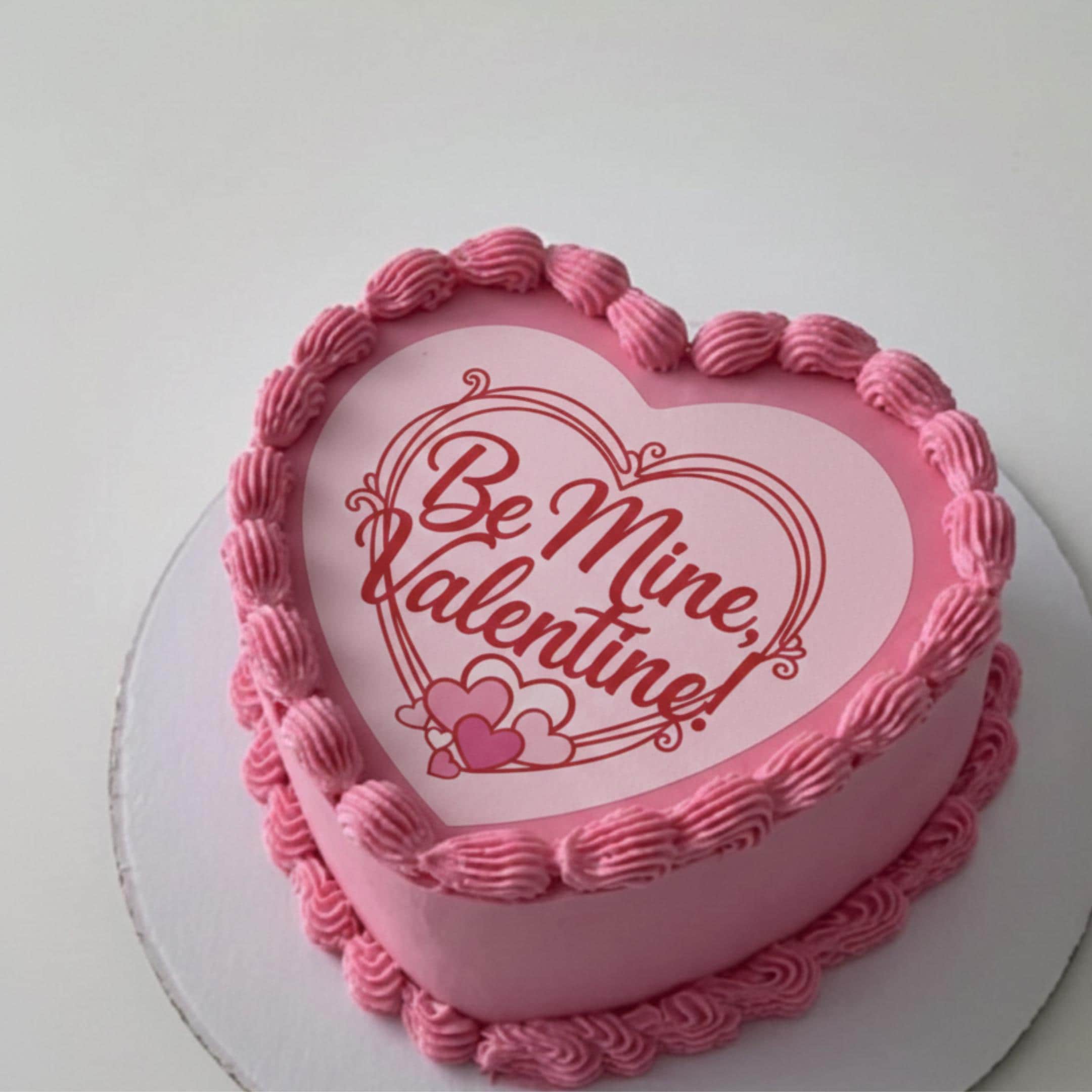 Round icing sheet cake topper with red heart frame and text Be Mine Valentine in script